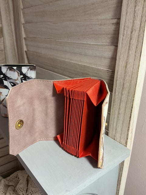 Open beige handbag with red interior lining on a surface.