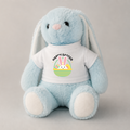 A light blue plush bunny toy wearing a white T-shirt with a colorful Easter graphic and the words 'HAPPY EASTER' on the front, photographed against a plain light gray background.