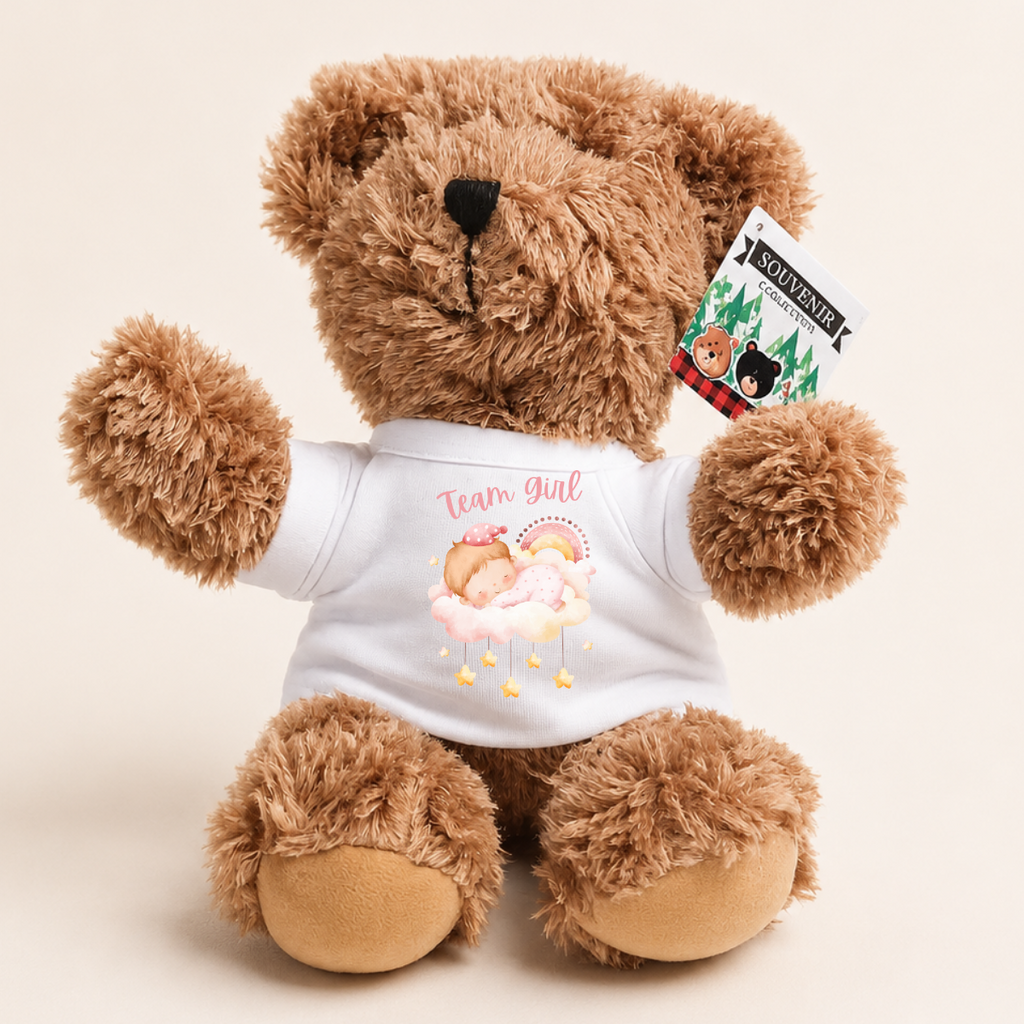A brown plush teddy bear wearing a white T-shirt with a pink and yellow 'Team Girl' graphic, shown against a light beige background. A hangtag on the ear reads 'SOWLAND'.