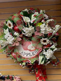 Decorative wreath with apples and flowers on a wooden surface