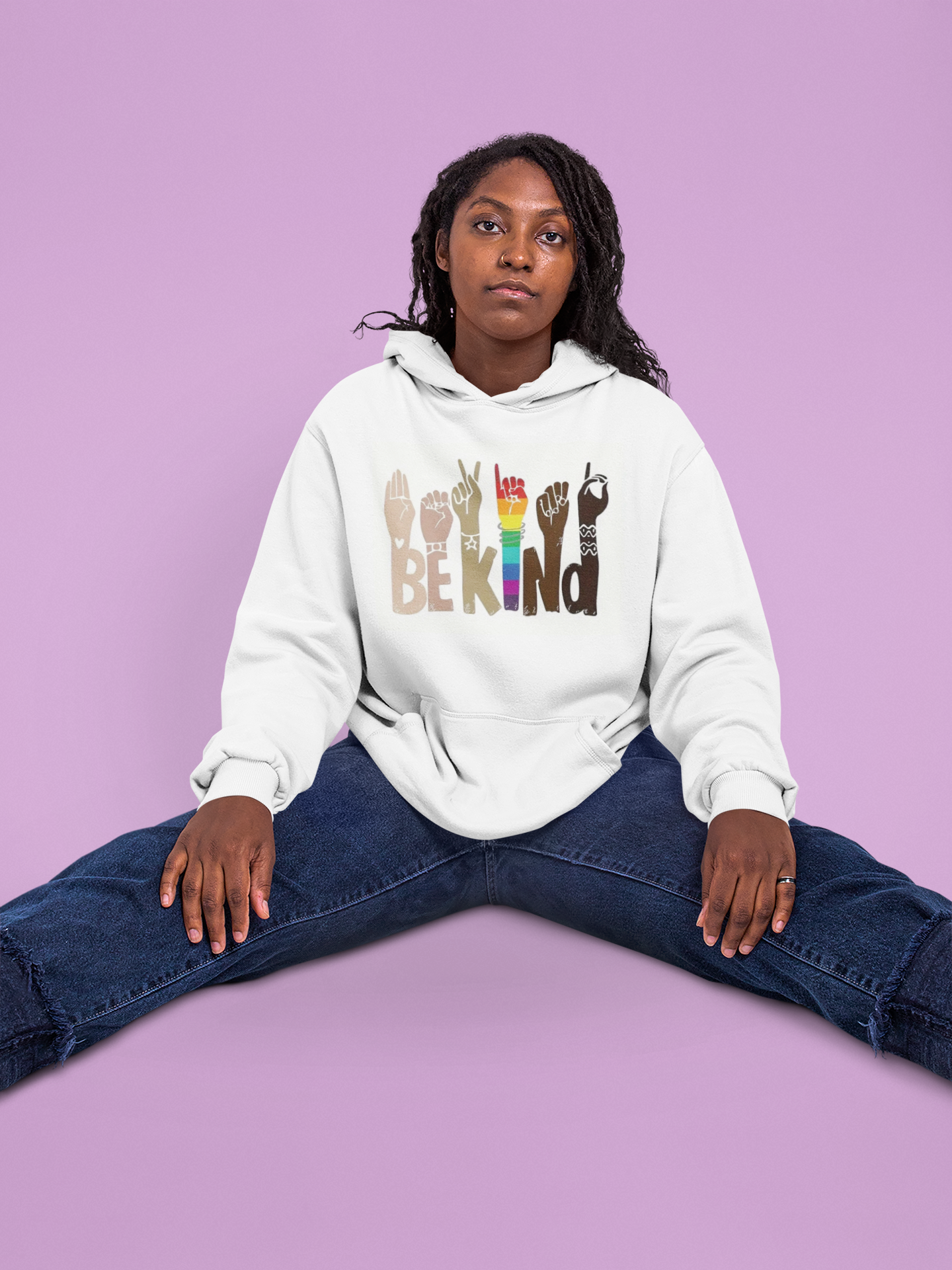 Person wearing a white hoodie with colorful text and symbols on a purple background