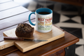 Mug with text on a wooden cutting board with a muffin