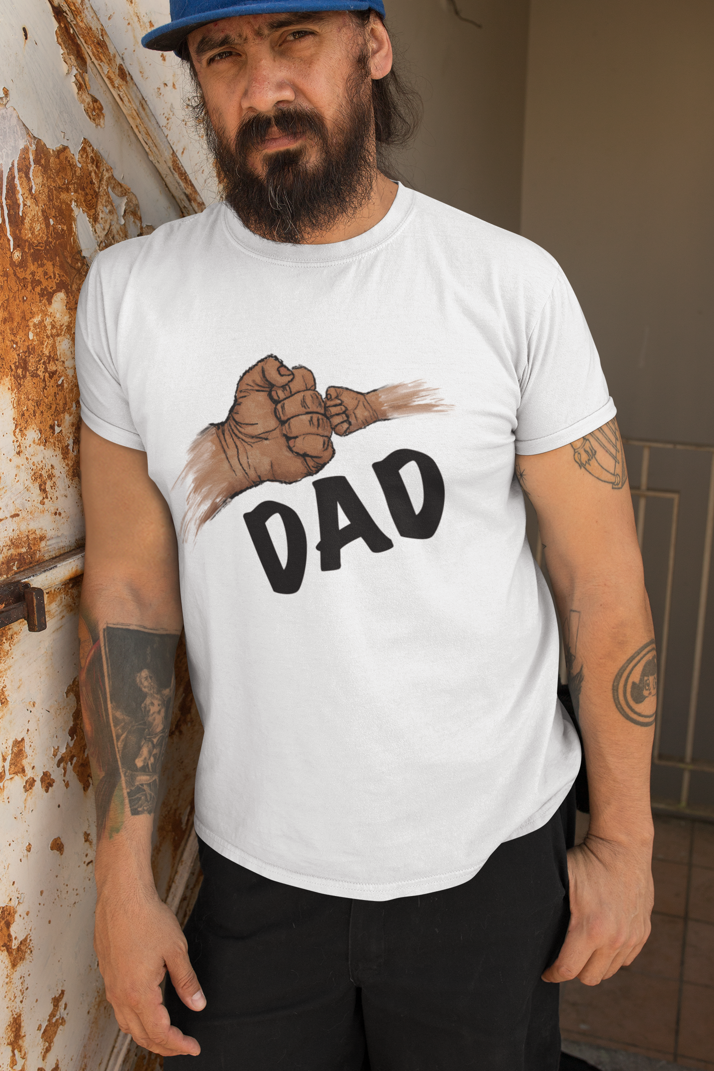 Man wearing a white t-shirt with a graphic and 'DAD' text, standing against a wall.