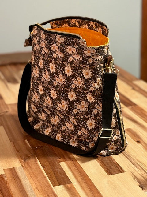 Floral-patterned bag with black strap on a wooden floor