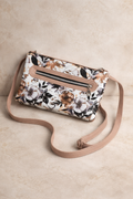 Floral patterned handbag with a beige strap on a beige background