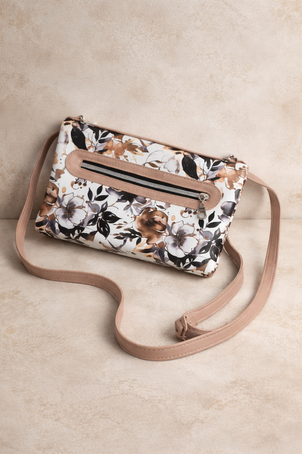 Floral patterned handbag with a beige strap on a beige background