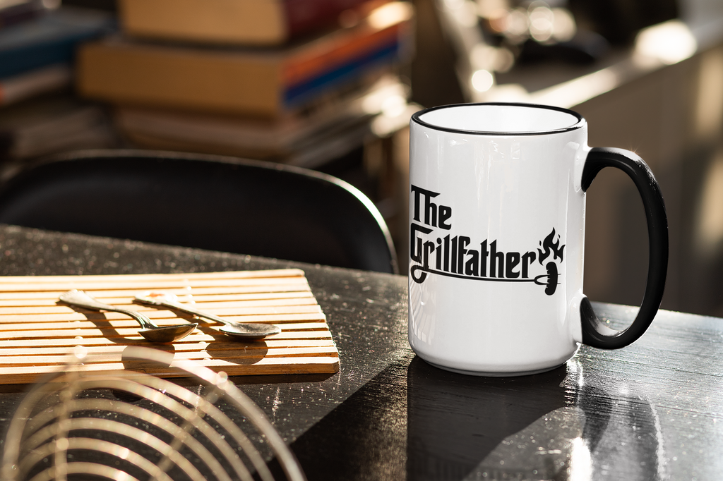 White mug with black handle and 'The Grillfather' design on a kitchen counter.