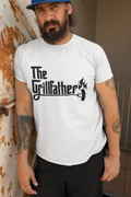 Man wearing a white t-shirt with 'The Grillfather' design, standing against a rusty metal wall.