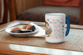 Mug with 'Happy Mother's Day!' text and design on a table with a plate of figs.