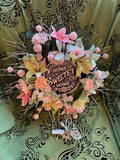 Decorative wreath with flowers and 'Home Sweet Home' sign on a patterned background