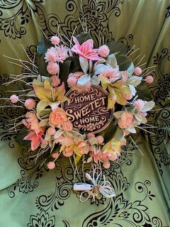 Decorative wreath with flowers and 'Home Sweet Home' sign on a patterned background