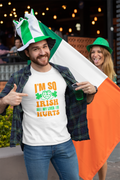Man wearing a white t-shirt with 'I'm so Irish my liver hurts' text, holding an Irish flag, and pointing at the text.