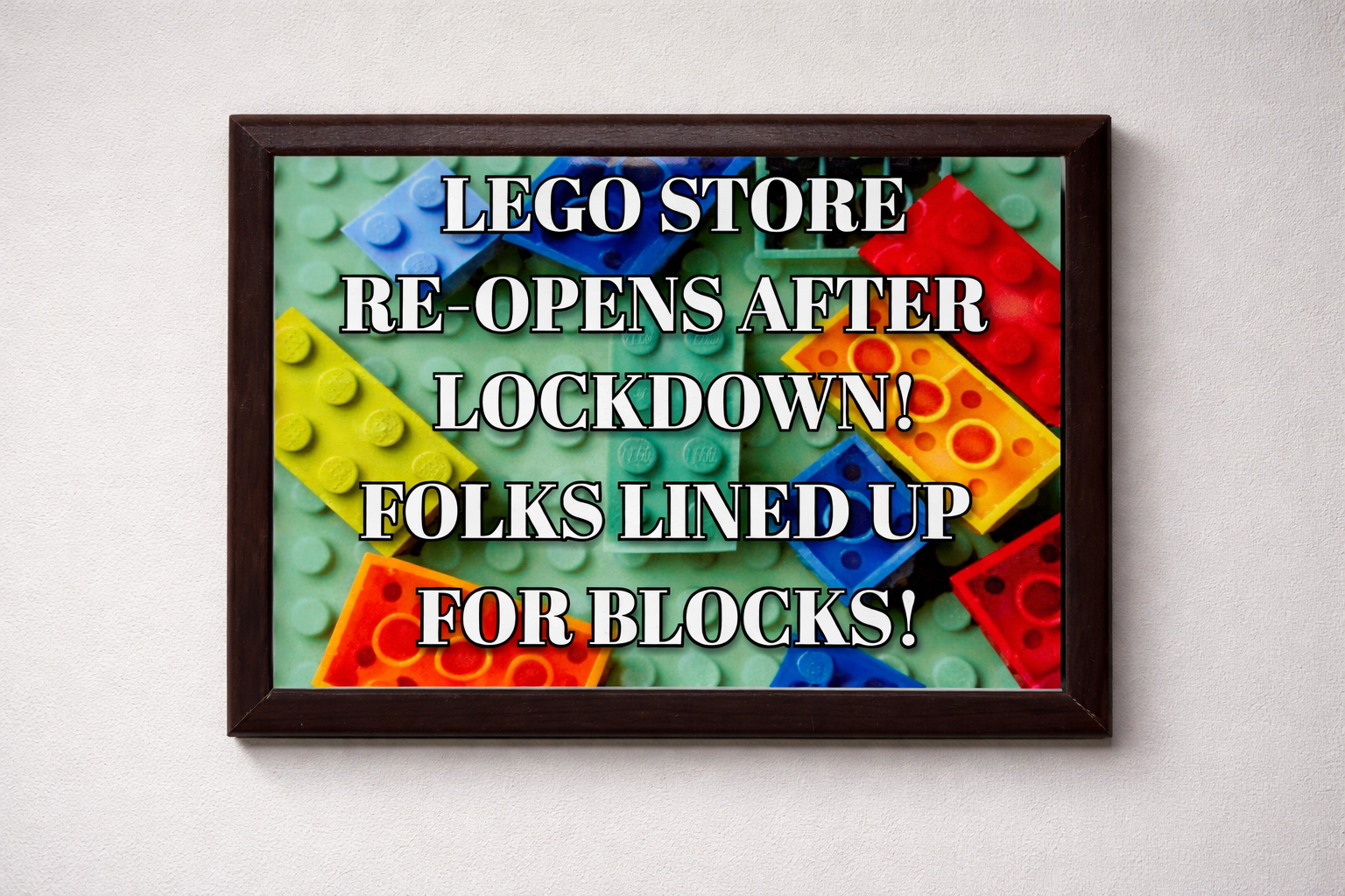 Framed poster with colorful LEGO bricks and text about a reopened LEGO store.