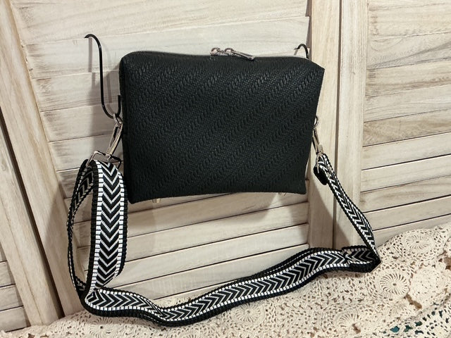 Black handbag with a decorative strap on a wooden surface