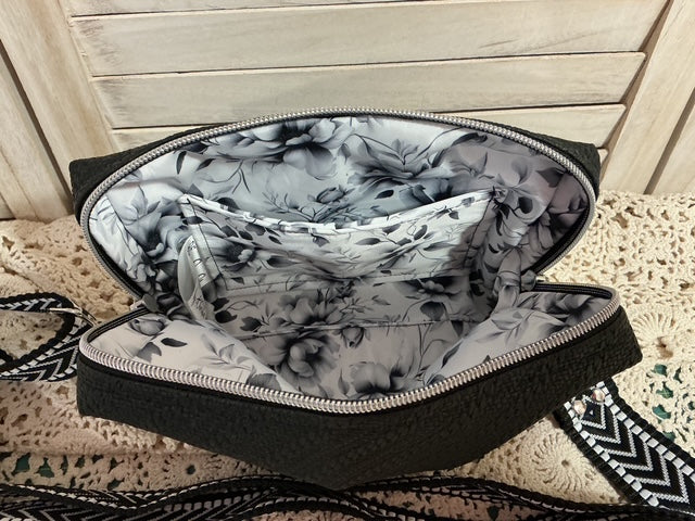 Black clutch bag with floral interior on a textured surface