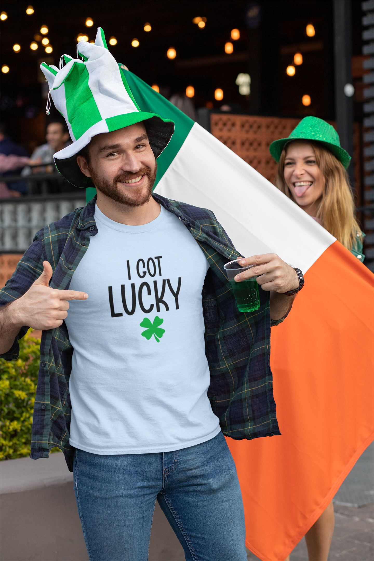 Man wearing a blue 'I Got Lucky' shirt with an Irish flag and green hat, standing outdoors.