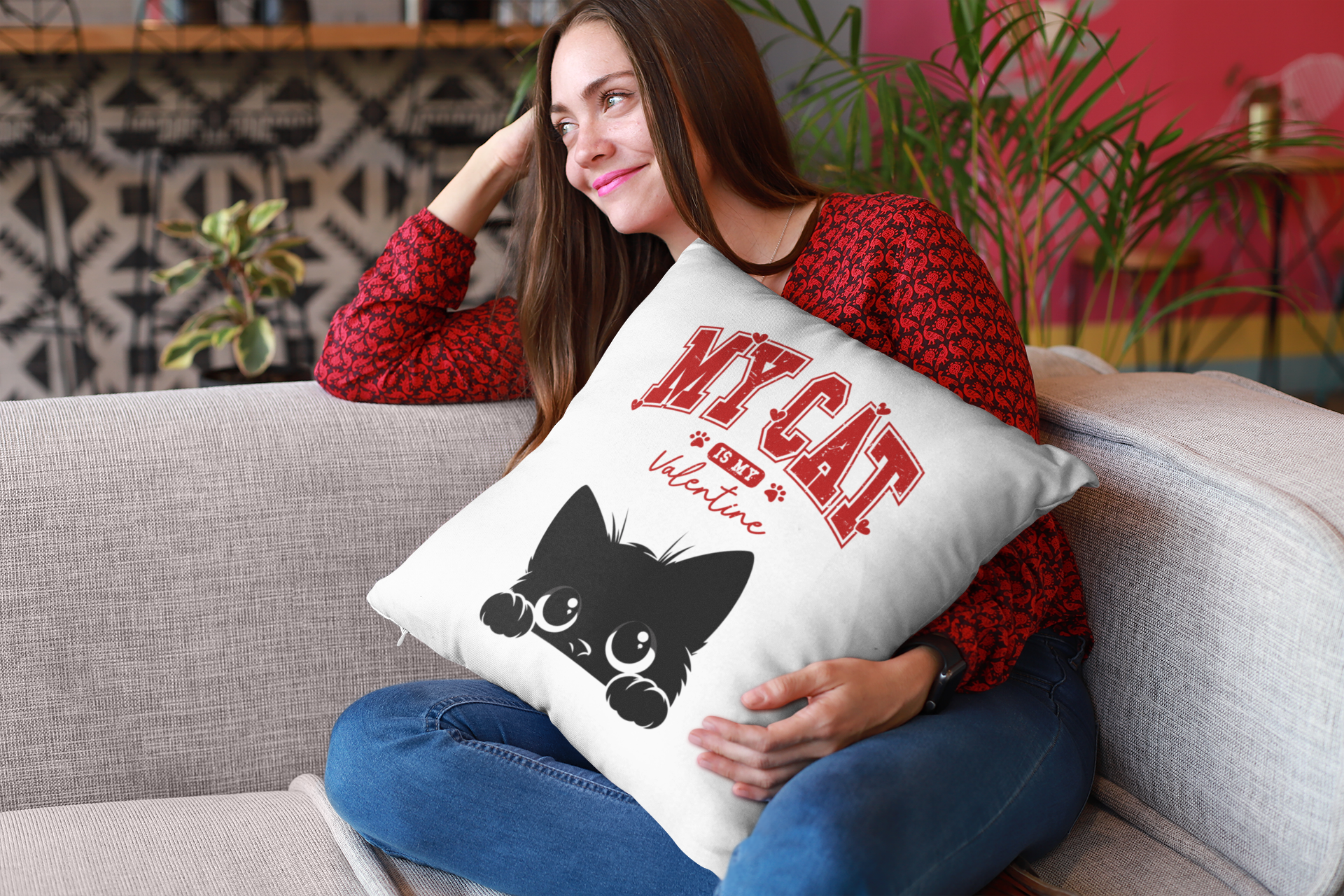 Woman holding a pillow with 'My Cat Valentine' text and a black cat illustration on a couch.