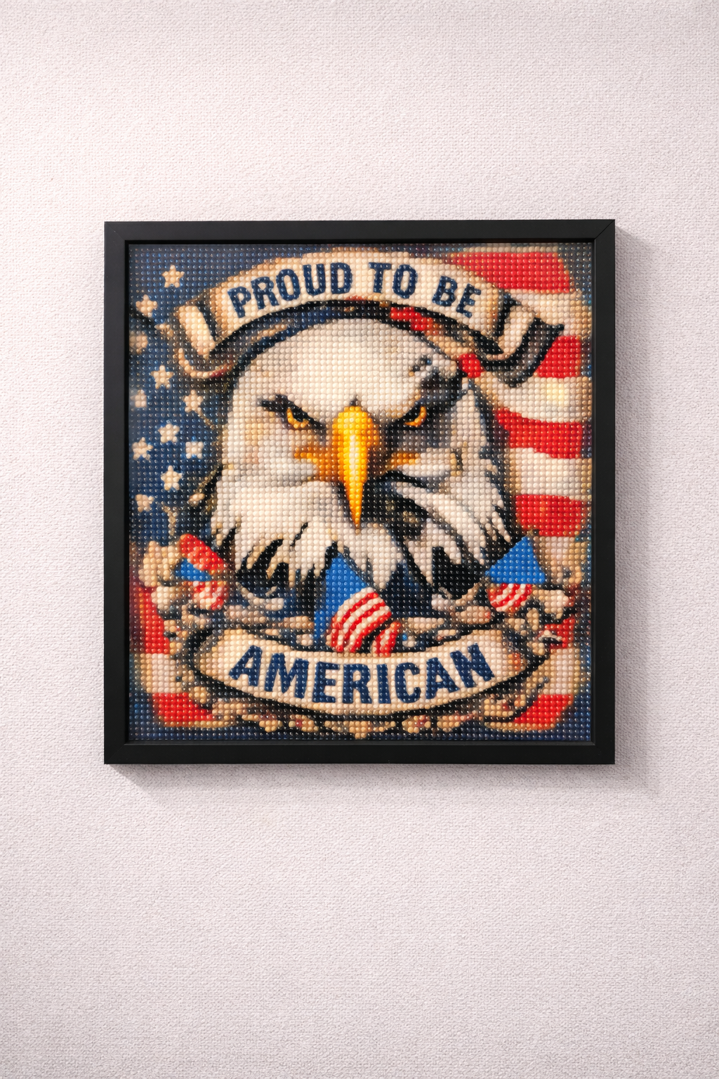 Framed artwork with an eagle and 'Proud to be American' text on a white wall.
