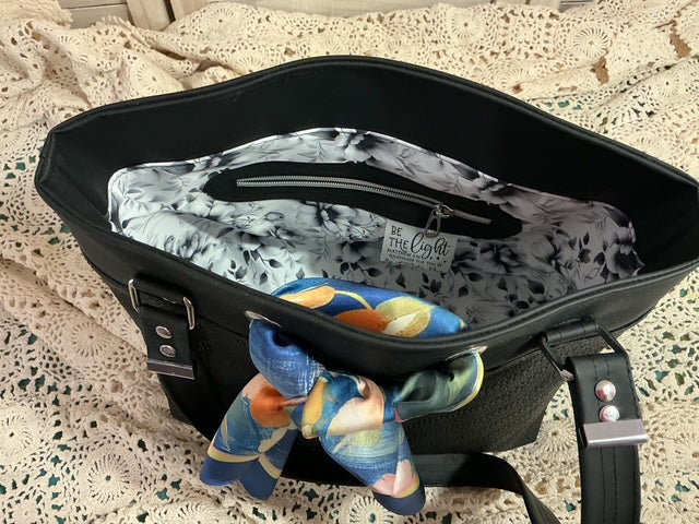 Black bag with floral-patterned items on a textured surface