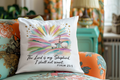 Decorative pillow with a colorful design and text on a floral couch.