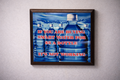 Framed poster with blue water bottles and text on a gray wall