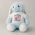A light blue plush bunny toy with long floppy ears, a pink nose, and a white T-shirt printed with the phrase 'Some Bunny Loves You' and a small bunny holding a basket of flowers.
