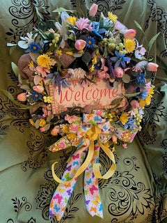Decorative wreath with flowers and a 'Welcome' sign on a patterned background