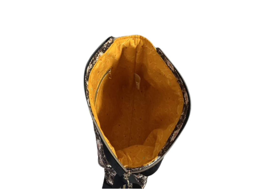 Close-up of a black and gold patterned bag with a yellow interior on a white background