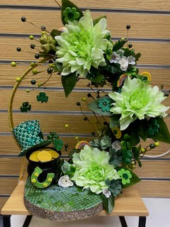 Decorative arrangement with green flowers and a small pot on a wooden surface.