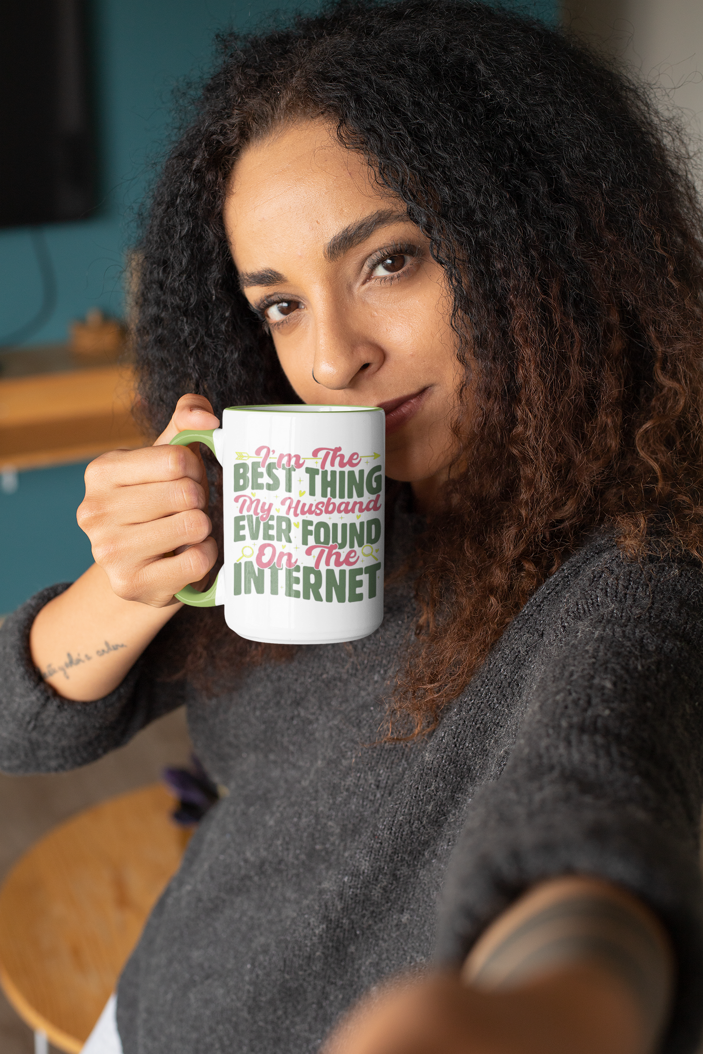 Woman holding a mug with text, sitting indoors.