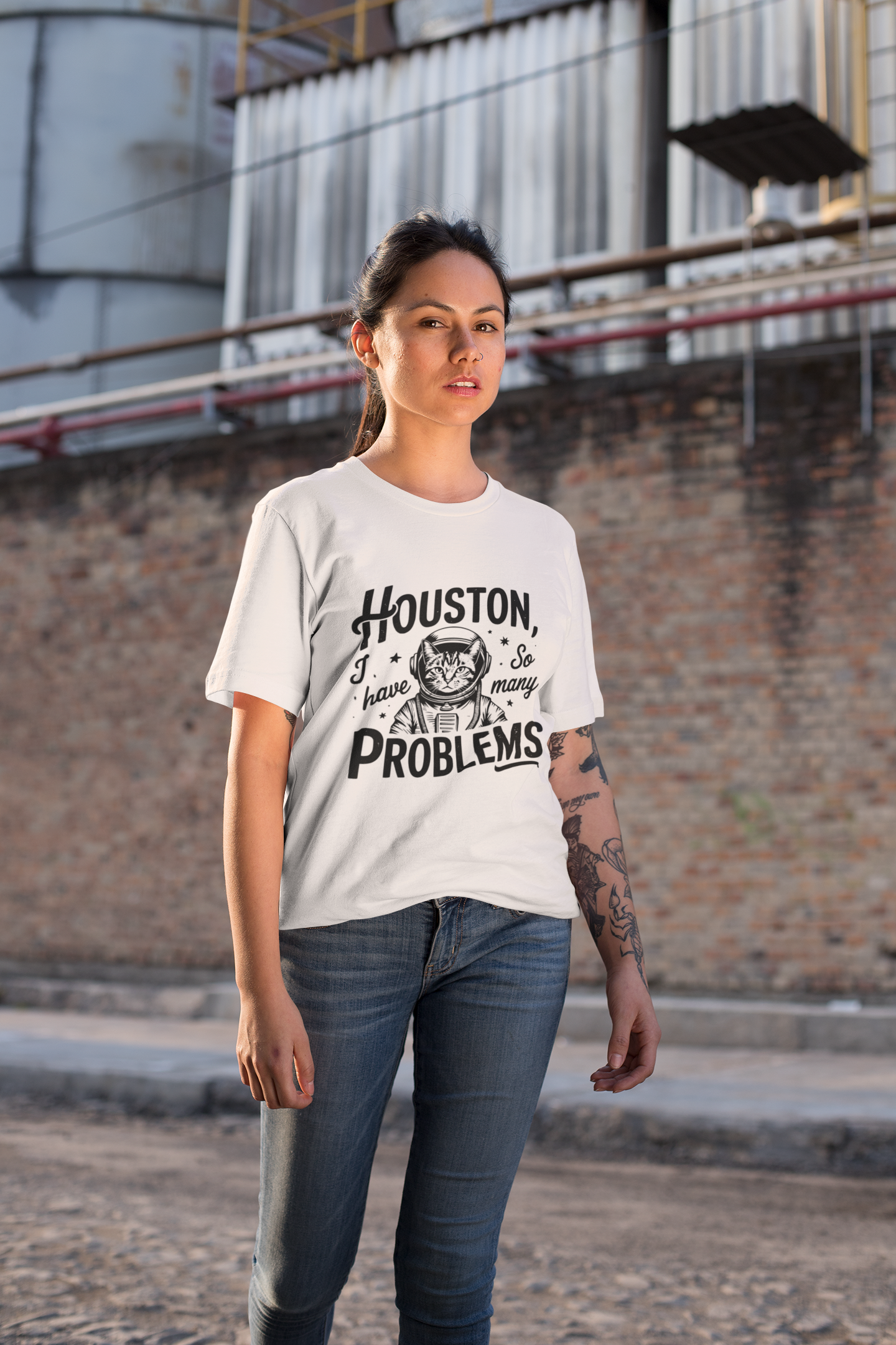 Woman wearing a white t-shirt with text standing in front of a brick wall.