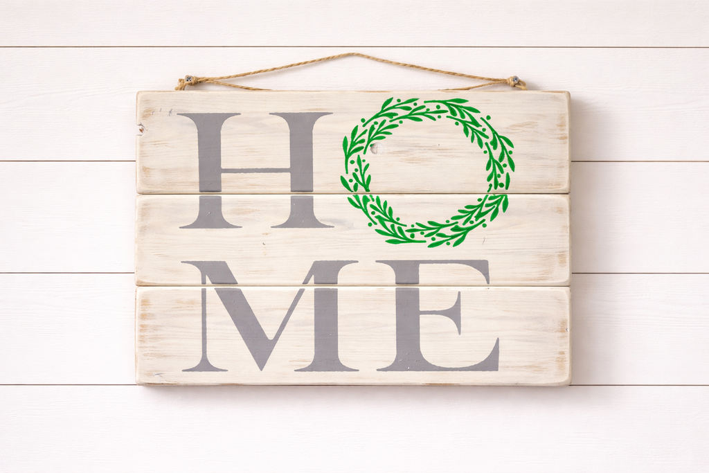 Wooden sign with 'HOME' and green wreath on a white wooden background