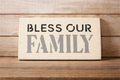 Wooden sign with 'Bless Our Family' text on a wooden background