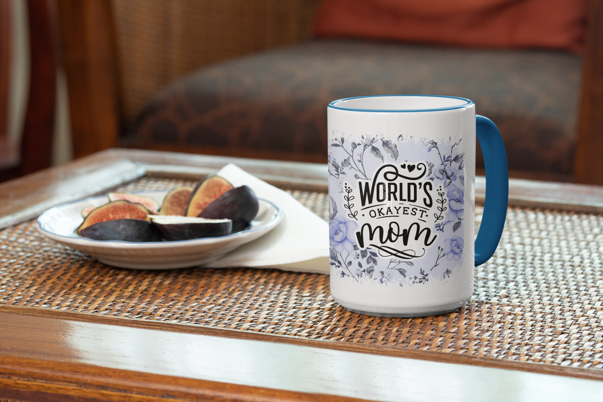 Mug with 'World's Okayest Mom' text on a table with figs