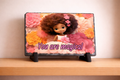 Decorative slate with a doll and floral design on a wooden surface